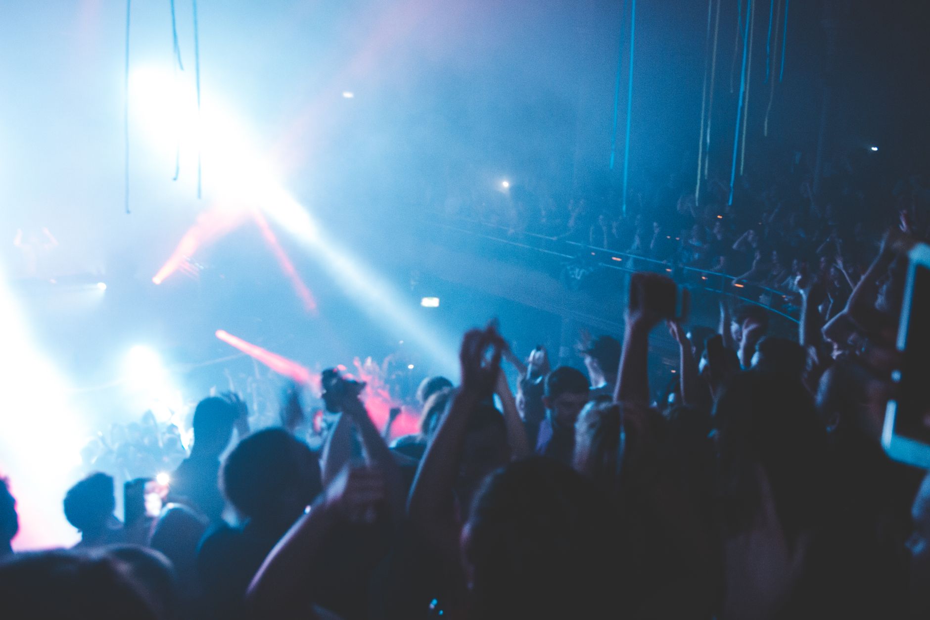 DJ performing to a packed dance floor with hands raised at a night event