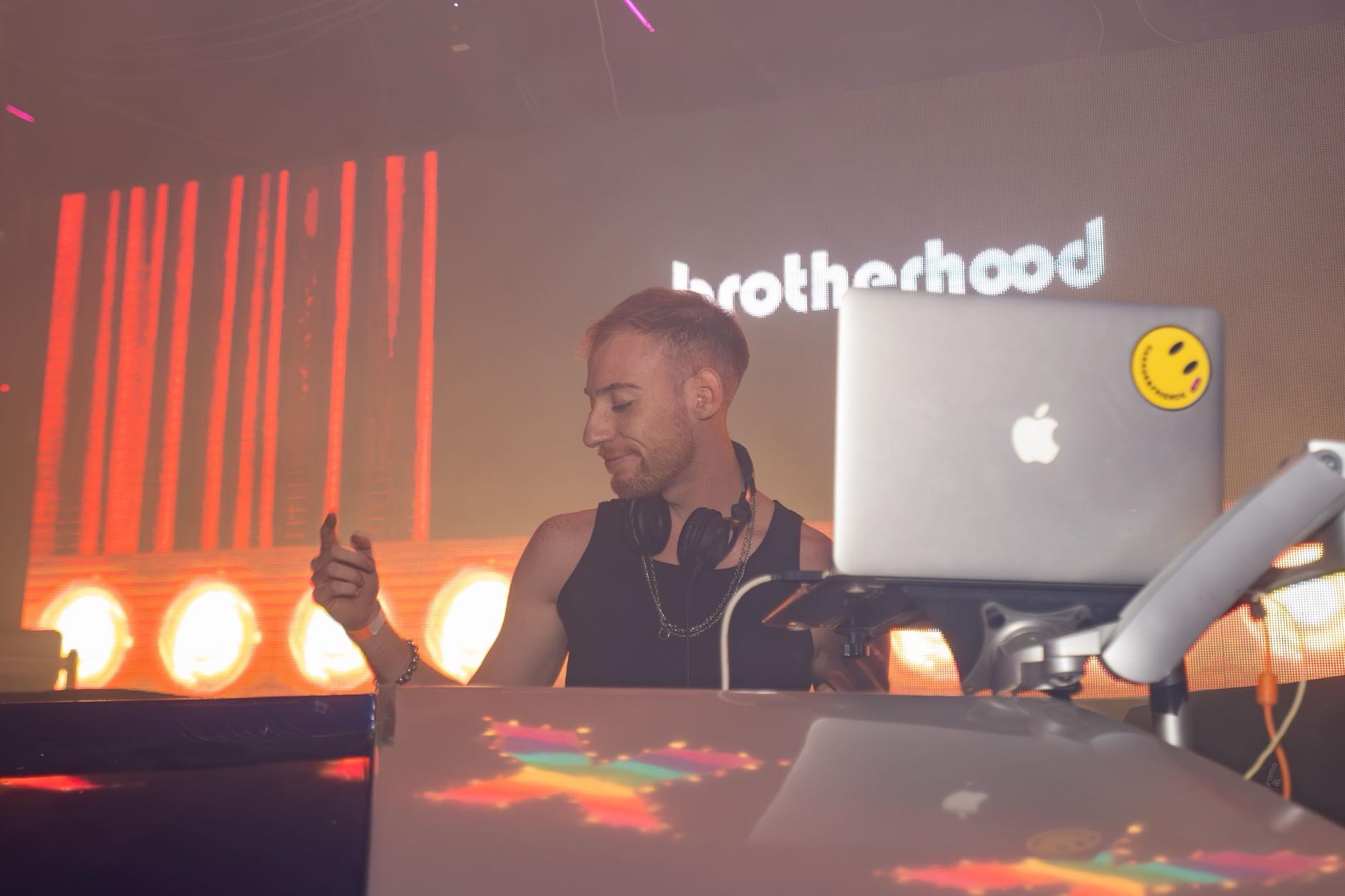 DJ scrolling through a laptop music library comparing beatport pricing to a pool subscription