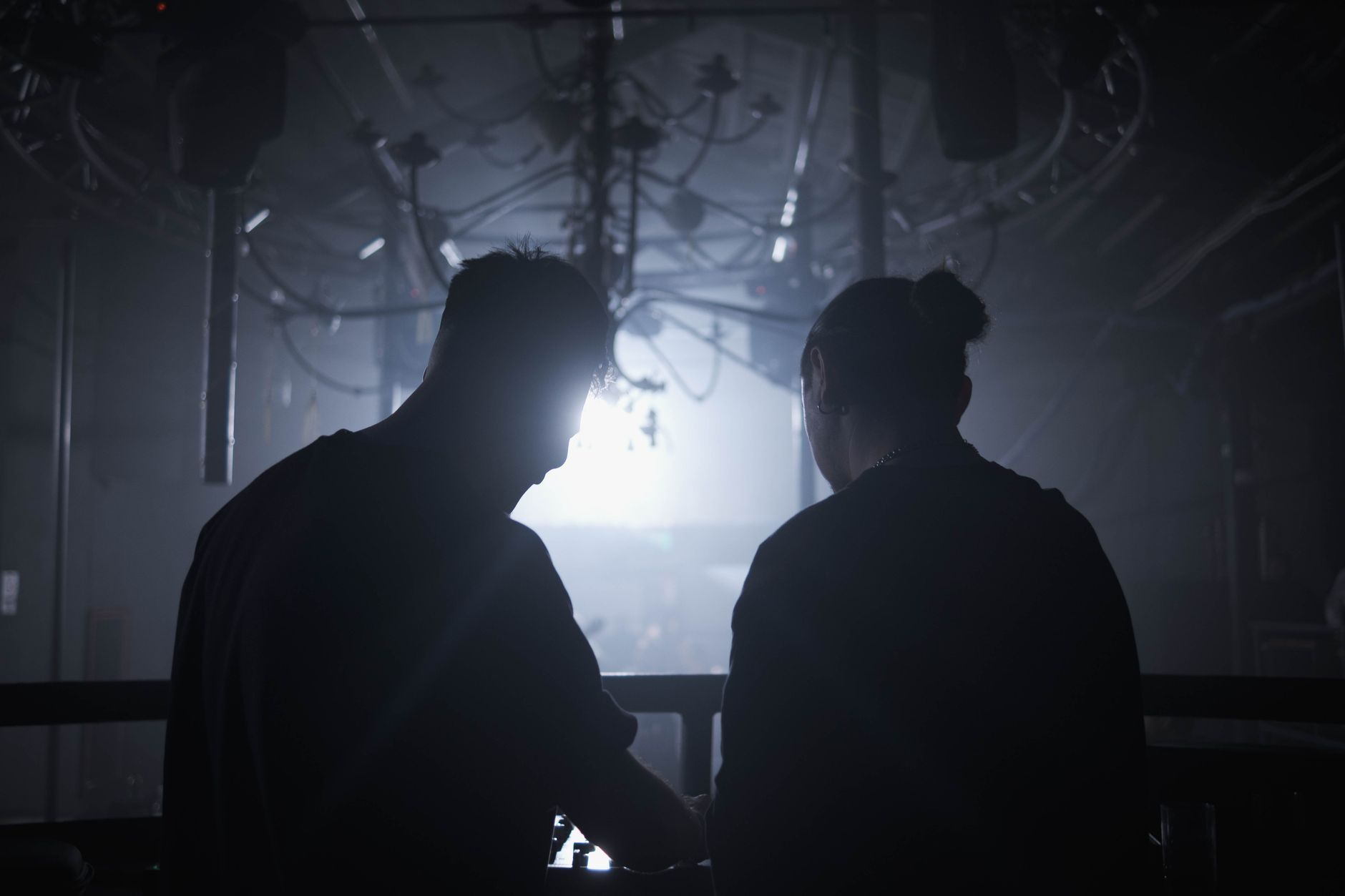 Two DJs standing backstage at a nightclub before their set