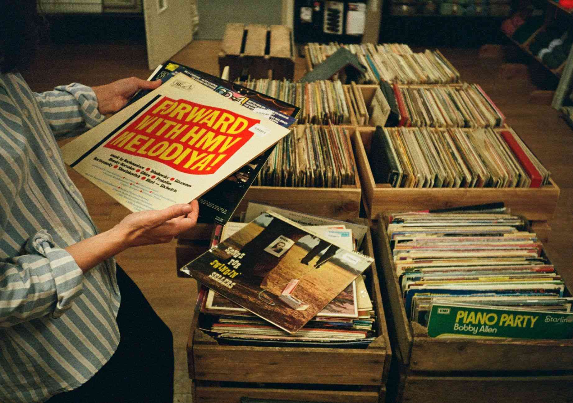 A DJ flipping through vinyl record crates, the original dj record pool format