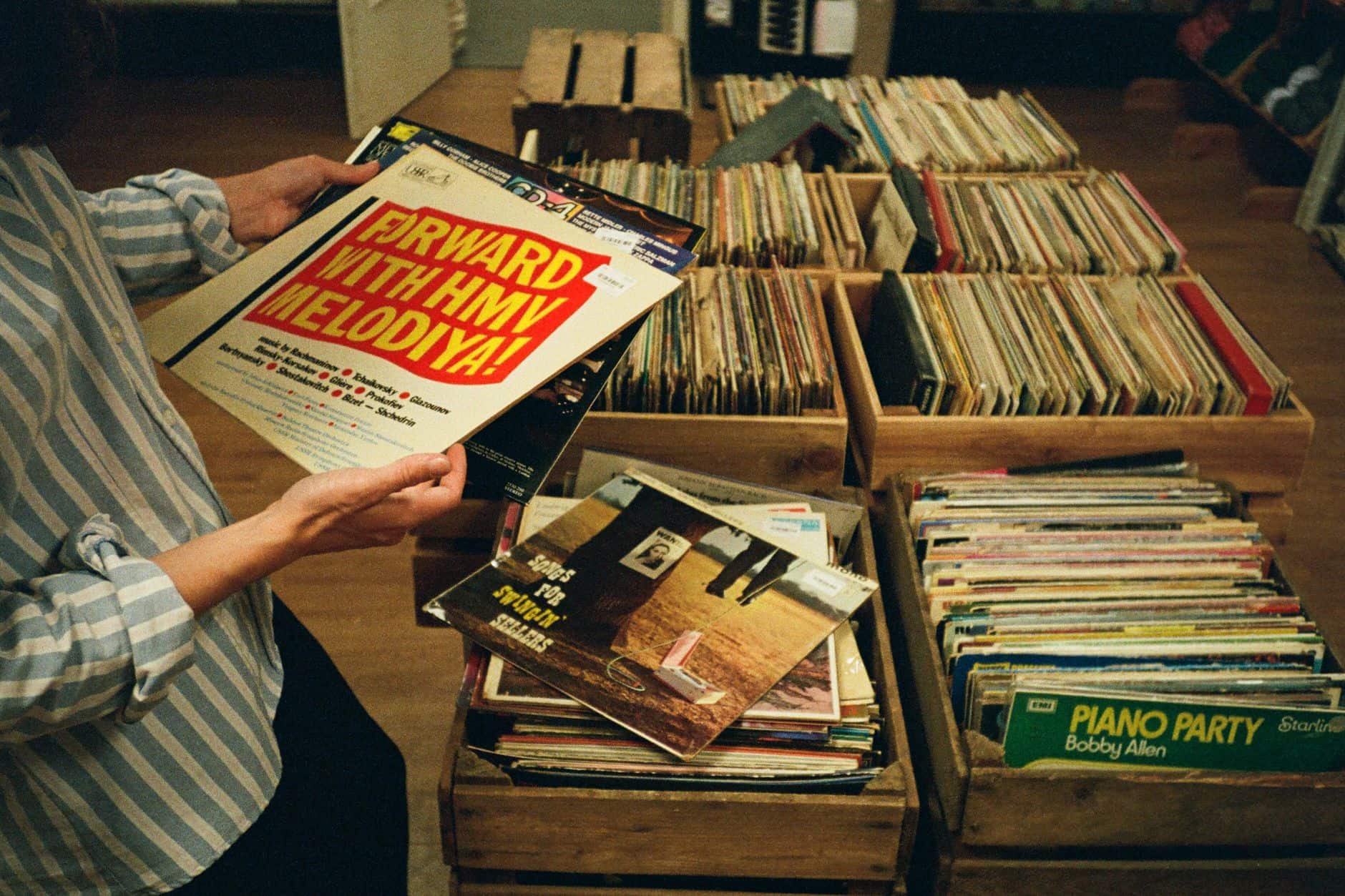 DJ crate-digging through vinyl and USB drives while filtering new tracks for a dj music library