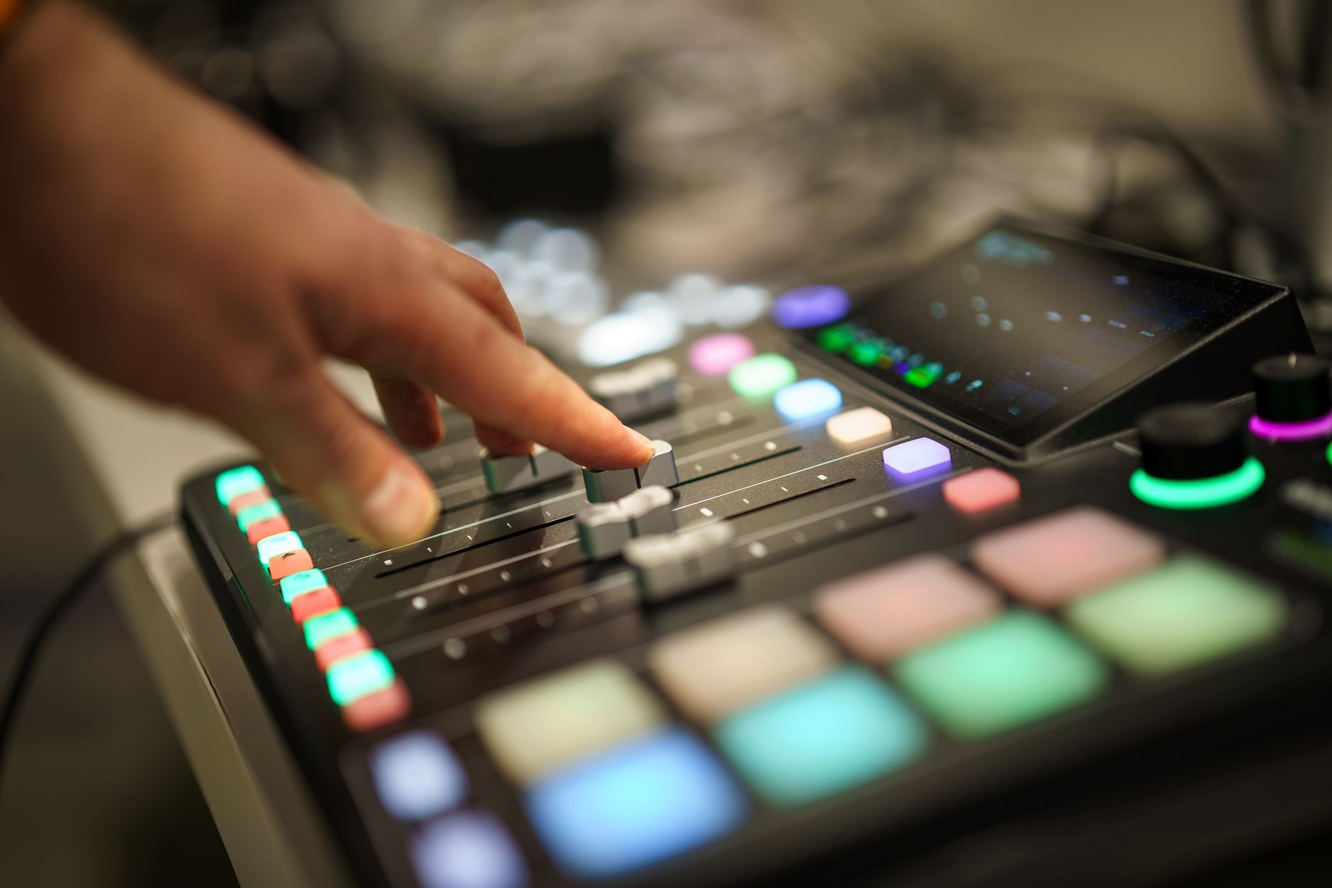 Close-up of DJ hands sorting tracks on a controller screen mid-prep