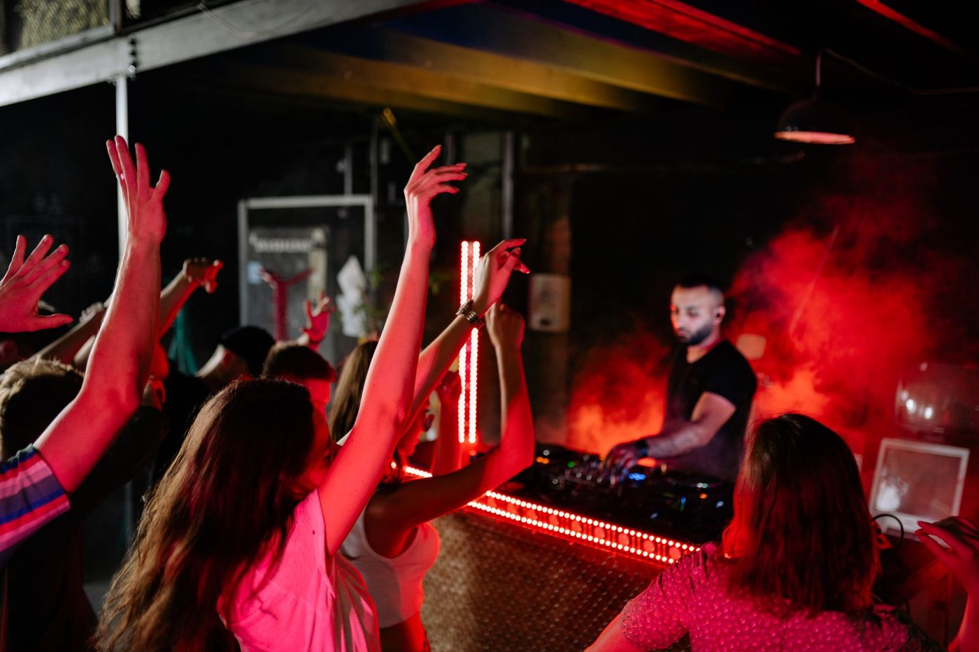 Crowd with hands up in front of a DJ booth mid-set