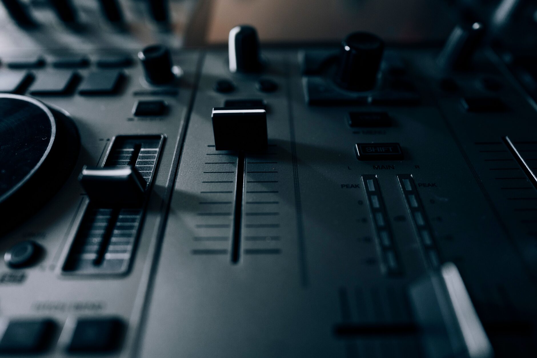 Close-up of a DJ's hand on a mixer during a set built from tracks sourced across multiple lanes